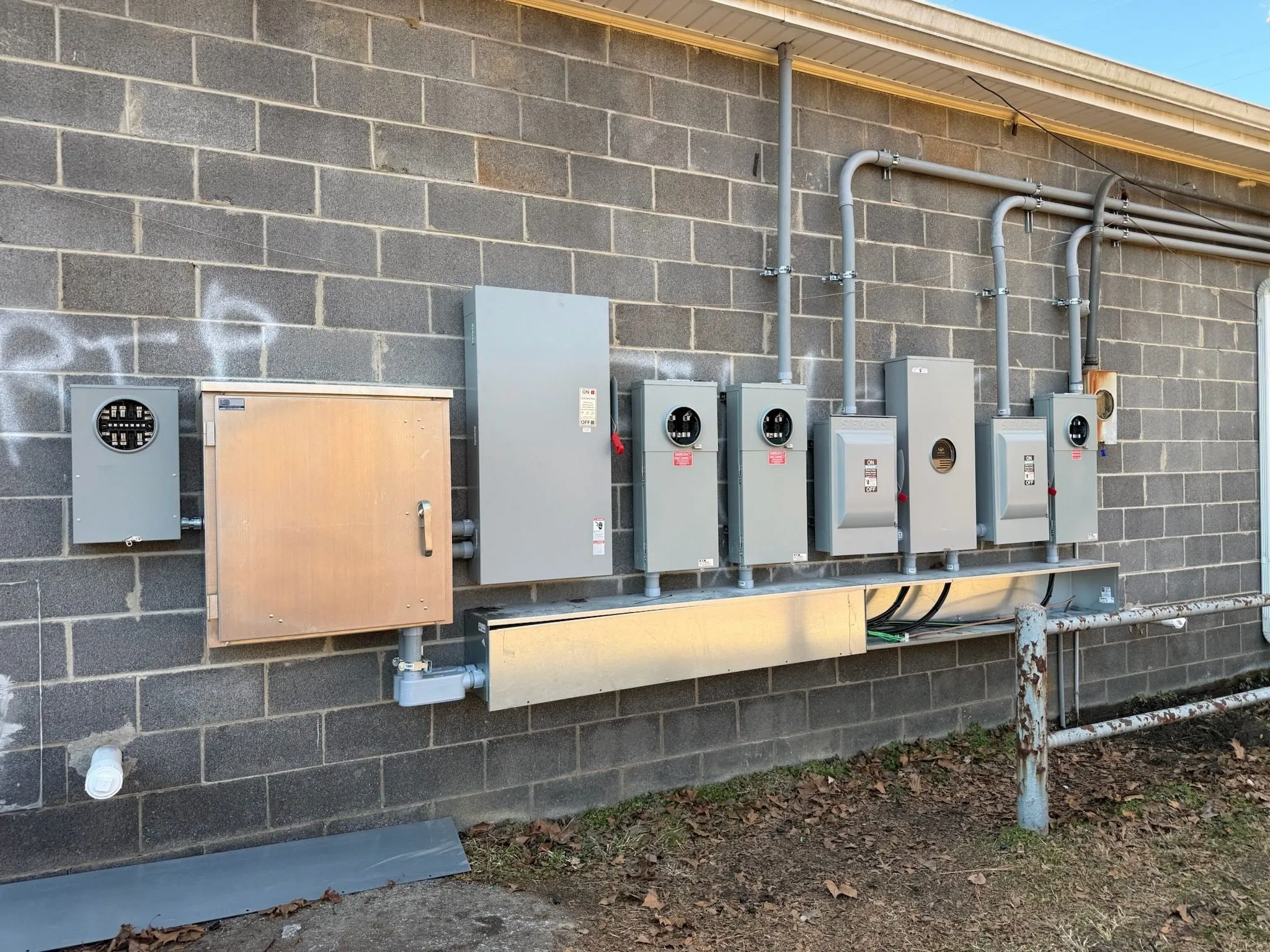 A row of new meters and disconnects grouped together on a block wall