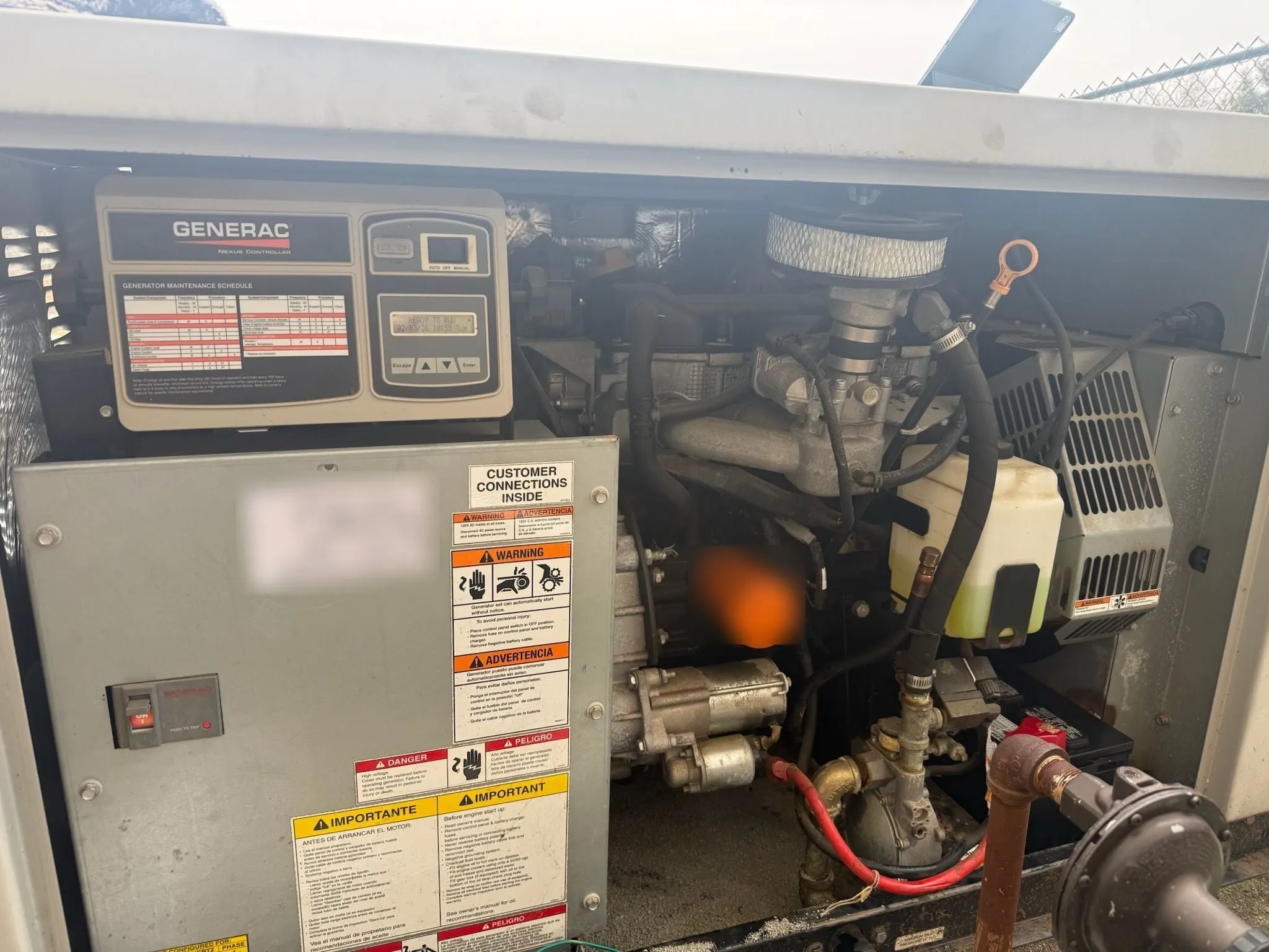 A Generac standby generator with its cover open, showing the controller, engine, air filter and oil filter