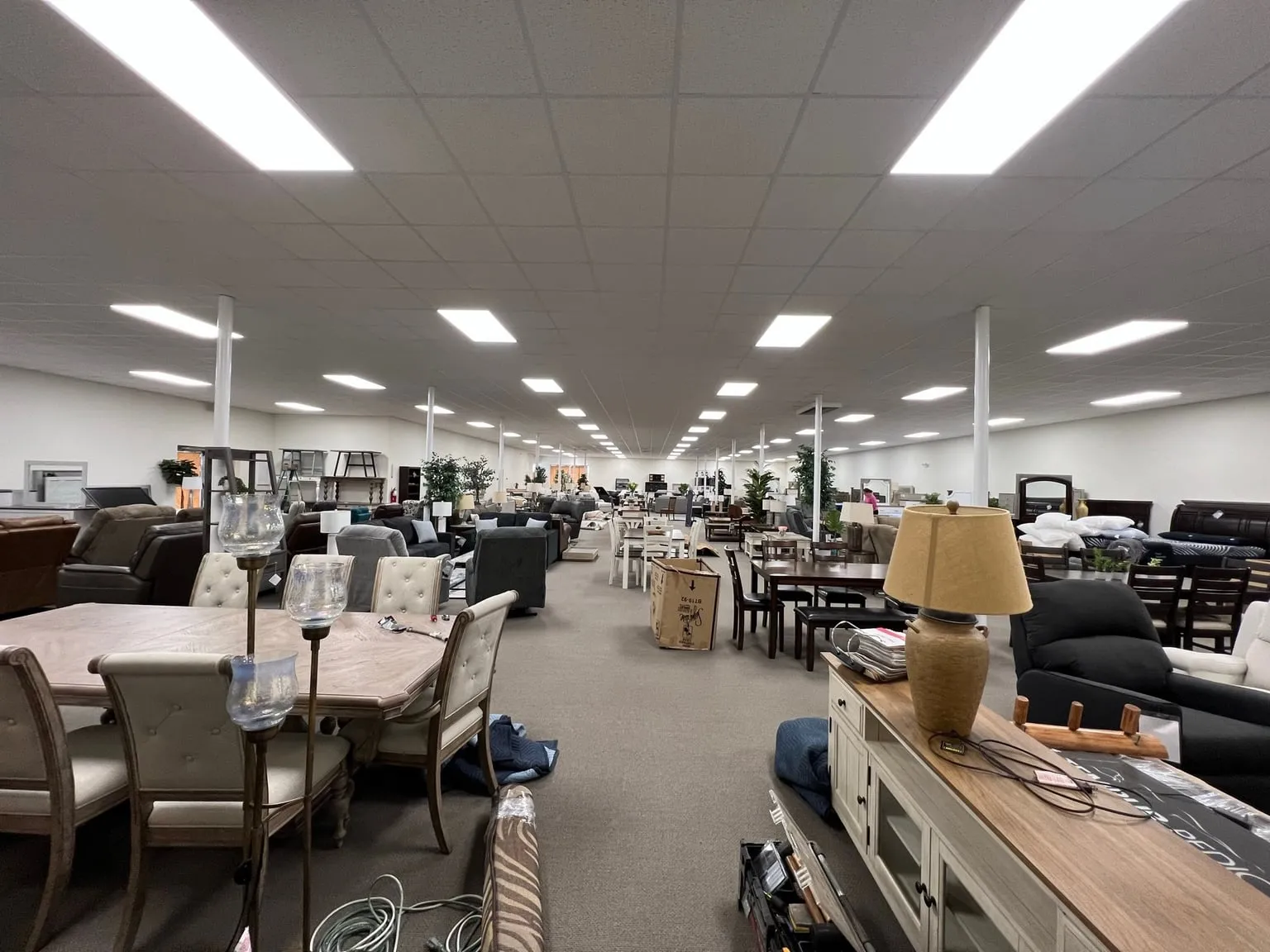 A long furniture showroom lit end to end by rows of flat ceiling light panels