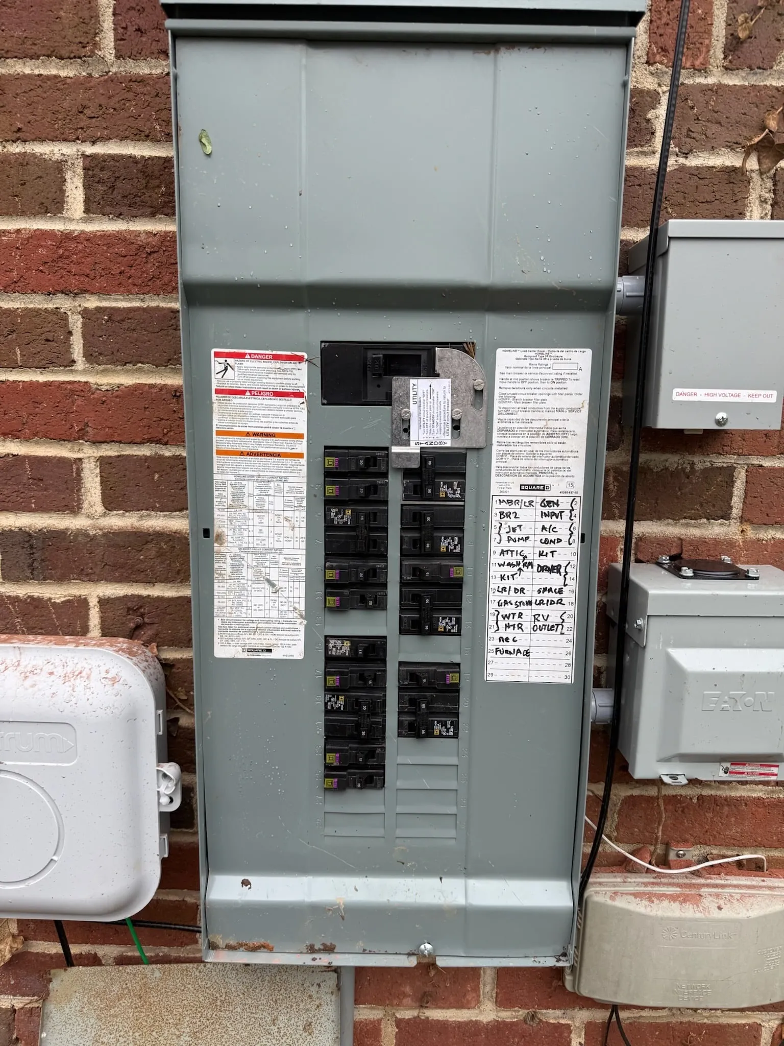 A new gray electrical panel on the same brick wall, with a typed and handwritten circuit directory, and new boxes mounted beside it