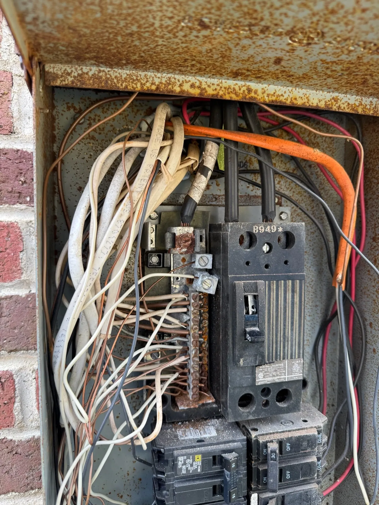 Inside the old panel: a rusted enclosure, a crowded tangle of wires and old breakers