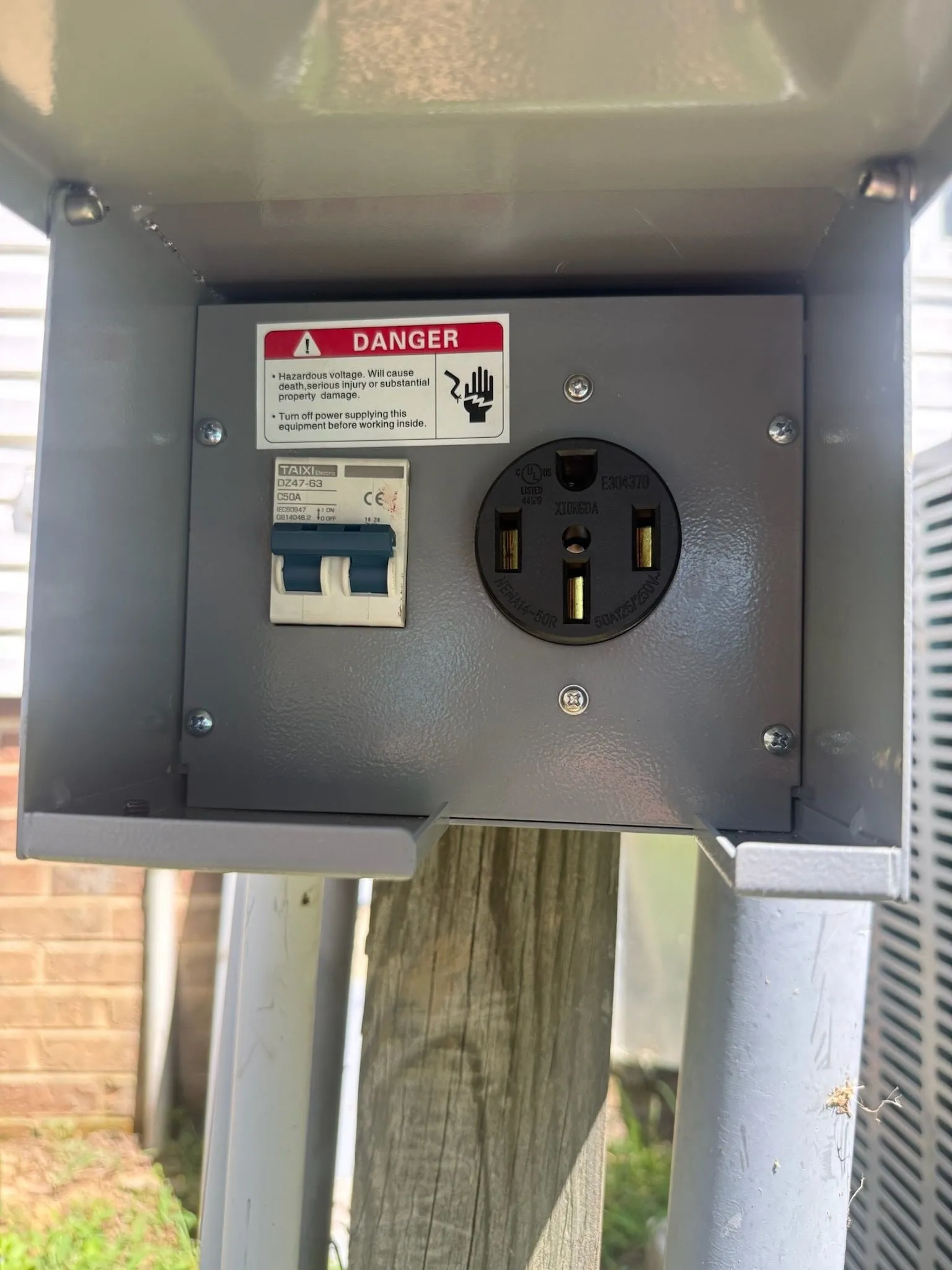 A 50-amp RV receptacle and its breaker in a metal box mounted on a wooden post